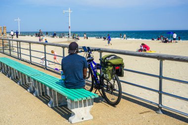 FAR ROCKAway, New York - 15 Mayıs 2020: Bisikletçiler Far Rockaway, New York 'taki Riis Park Tahta Yolu' nda COVID-19 pandemisi sırasında açık havanın tadını çıkarıyorlar