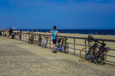 FAR ROCKAway, New York - 15 Mayıs 2020: Bisikletçiler Far Rockaway, New York 'taki Riis Park Tahta Yolu' nda COVID-19 pandemisi sırasında açık havanın tadını çıkarıyorlar