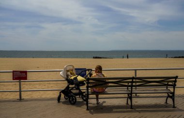 BrooKLYN, NEW YORK - 20 Mayıs 2020: Yayalar ve bisikletçiler, New York, Brooklyn 'deki Coney Island Beach' teki Riegelmann tahta yolunda COVID-19 salgını sırasında açık havanın tadını çıkarıyorlar. 