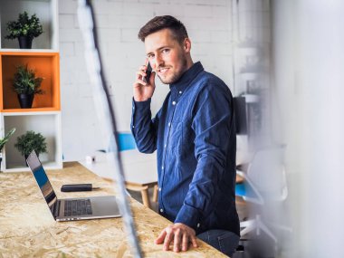 Mavi gömlekli bir adam birlikte çalıştığı ofiste dizüstü bilgisayar kullanıyor, uzaktan kumandalı internet işi ve karantina ofisi.