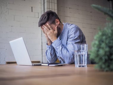 Mavi gömlekli bir adam birlikte çalıştığı ofiste dizüstü bilgisayar kullanıyor, uzaktan kumandalı internet işi ve karantina ofisi.