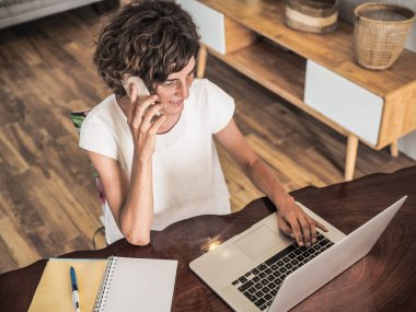 Bilgisayarlı uzaktan kumandalı çalışan kadın akıllı konuşuyor, ev konseptinden çalışıyor. 