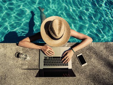 Yüzme havuzunda dizüstü bilgisayarı olan genç bir kadın 