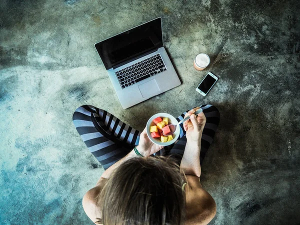 Ung Kvinna Äter Frukt Tittar Laptop Ovanifrån — Stockfoto