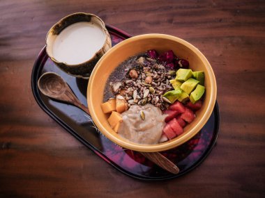 Tahta kaşıklı vegan meyve kasesi, granola, chia, tohum, mango, ejderha meyvesi, karpuz, avokado 