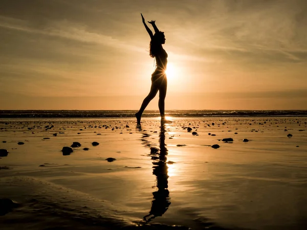 サンセットの砂浜でヨガをしている若い女性は — ストック写真