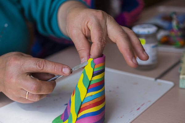 Teaching students the art of modeling. Sculpture made of plasticine. A girl molds a doll with her hands.