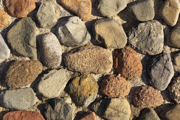 Background of colored stones. The surface is decorated with natural material. Pattern on the floor of multicolored pebbles.