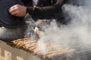 Et dilimleri ateşte hazırlanıyor. Şişte pişmiş et. Bir aşçı dışarıda sıcak bir yemek hazırlıyor. Efendinin elleri..