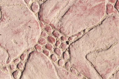 Bir deseni olan kaldırım taşları. Kırmızıya boyanmış beton bir levha. Dış dekorasyon için dekoratif öge.