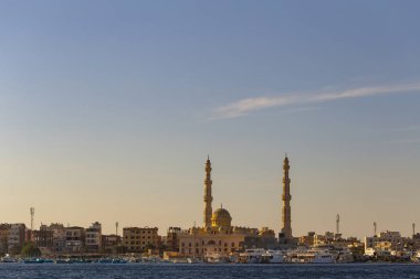 Hurghada, Mısır, gün batımında bir şehir. Kızıl denizden antik şehir manzarası. Panoramik manzara. Gemili bir liman ve camili bir yerleşim yeri..