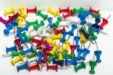 Kağıtları tutturmak için keskin bir iğne. Renkli kırtasiye düğmeleri açık arkaplanda serili. Eğitim için karanfiller. Kağıt iliştiriyorum. Ofis sayfası.