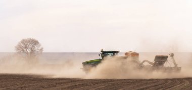 Tohum eken bir traktör tarıma elverişli arazide çalışıyor. Tarım işi. Bahar ekili tahıl..