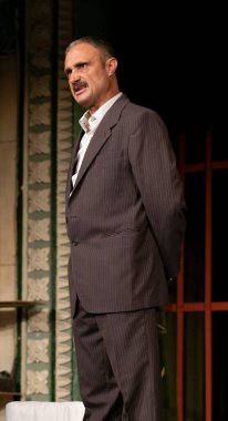 Sahnede takım elbiseli tuhaf bir adam. Duygu öfkedir..