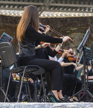 Meydanda, şehir sakinlerinin önünde bir yardım konseri. Açık hava konserinde klasik müzik çalıyor. İnsanlar müzik aletleri çalıyor..