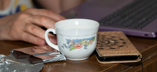 自我隔离 远程工作 有鼠标 笔记本电脑 咖啡杯 电话和巧克力的女人的手 — 图库照片