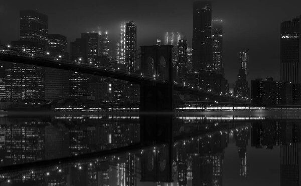 Black and white night view of Brooklyn Bridge and Manhattan downtown skyline