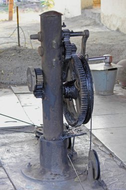 Traditional cast iron cranck gear and cables manually lift and drop the railway junction gate, India