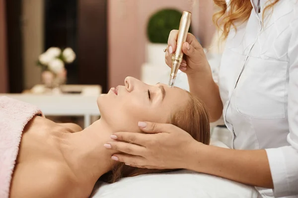 Hermosa mujer recibiendo procedimiento de descamación de la cara en una clínica de belleza, retrato de cerca. Chica con la piel de la cara perfecta en un procedimiento de lifting facial no quirúrgico. Tratamiento facial rejuvenecedor . — Foto de Stock