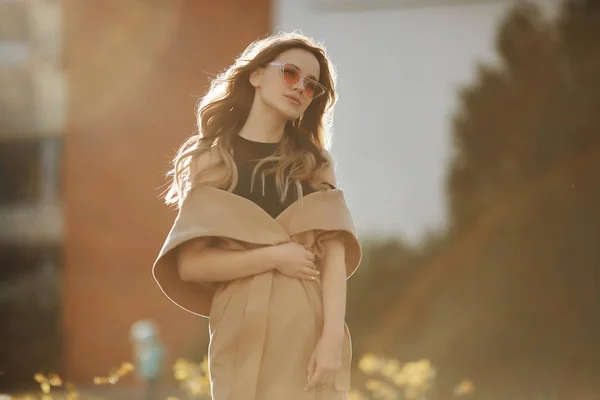 Fashionabla vackra och sensuella blonda modell flicka i ärmlös rock och snygga solglasögon njuter av solen och poserar utomhus på stadens gata — Stockfoto
