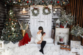 junge und schöne Frau in weißem Strickpullover und Strümpfen, die im weihnachtlichen Interieur posieren. Modische Brünette Modell Mädchen mit sexy Beinen posiert mit Tasse Kaffee im Inneren für das neue Jahr dekoriert