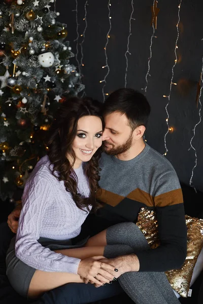 Portrait de jeunes beaux amants à l'intérieur de Noël. Beau homme et jeune beauté dans une tenue élégante passer la soirée de Noël ensemble dans l'intérieur confortable décoré pour les vacances du Nouvel An — Photo