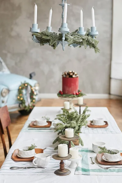 Festive table served for the Christmas brunch with beautiful festive dishes, glass, candelabra with candles and fir branches. Christmas eve. New year party.