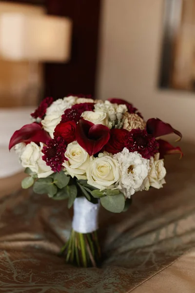 Lush bridal bouquet of exotic flowers, closeup, blurred background. Concept wedding postcard. Luxury bridal bouquet with calla lilies and peony roses. Delicate wedding bouquet in white and red colors