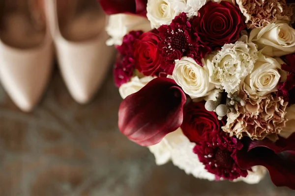Schöne bunte Brautstrauß und Brautschuhe aus dem Fokus. modische Brautstrauß aus Pfingstrosen, Rosen und exotischen Blumen. Nahaufnahme von Hochzeitsmode. Hintergrund für Hochzeitseinladung — Stockfoto