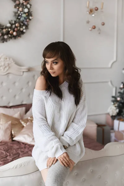 年轻美丽的女人,一头乌黑的头发,穿着时髦舒适的衣服,装饰着圣诞卧室. 在新的一年里，穿着针织服装和长袜，身材完美的性感模特 — 图库照片