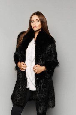 Lüks kürklü mükemmel makyajlı, arka planda soyutlanmış güzel bir manken kız. Şık kürklü, esmer ve şehvetli bir kadının moda stüdyosu fotoğrafı. Kış güzeli
