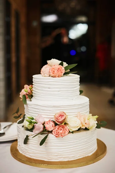 Weiße Hochzeitstorte mit rosa und weißen Blüten von Pfingstrosen und Rosen. extra große dreistöckige Hochzeitstorte mit weißem Buttercreme-Zuckerguss und frischen rosa und weißen Blüten. Luxus-Geburtstagstorte — Stockfoto