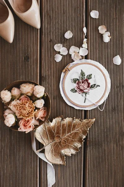 Rose and peonies flowers in a round box, wedding rings on the golden leaf, bridal shoes on high heels on wooden background, top view. Wedding details in the morning before the wedding ceremony. — 图库照片