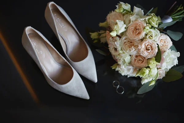 美丽的鲜花，新鲜的玫瑰，牡丹，桉树花，粉红，奶油色和其他新娘饰物。 婚礼前的结婚戒指、新娘花束和新娘鞋子. — 图库照片