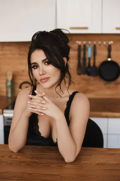 Retrato de menina modelo peituda sensual em uma roupa sexy preta olhando na câmera e posando na cozinha. Jovem com seios grandes e lábios cheios no interior da cozinha. Cozinheiro sexy — Fotografia de Stock