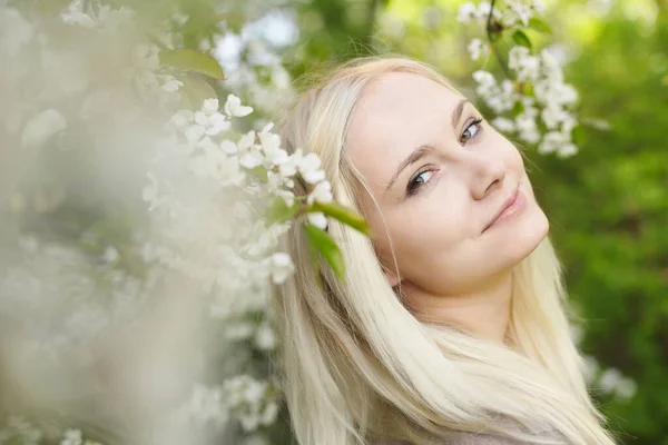 Portrait d'une belle jeune femme blonde parmi les arbres à fleurs — Photo