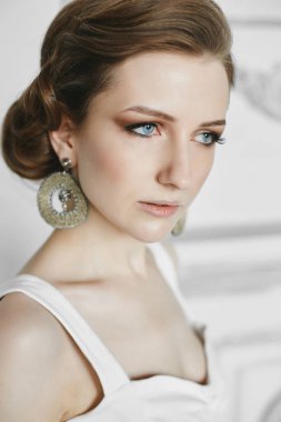 Güzel mavi gözlü ve parlak makyajlı esmer bir kadının portresi. Moda saç stili ve lüks küpeleri olan, modaya uygun iç mimari model bir kız. Güzellik stüdyosu. Makyaj kavramı