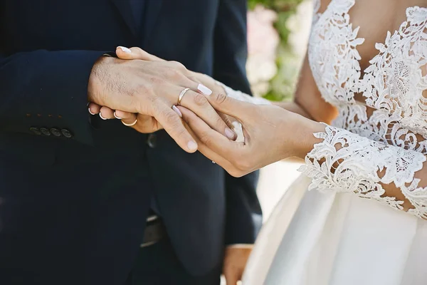 Die Braut trägt einen goldenen Ehering am Finger des Bräutigams. Nahaufnahme von schönen weiblichen und männlichen Händen bei der Trauung. Junges Hochzeitspaar bei Brautzeremonie — Stockfoto