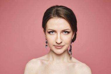Güzel, seksi ve modaya uygun, mavi gözlü, pembe arka planda soyutlanmış esmer kız portresi.