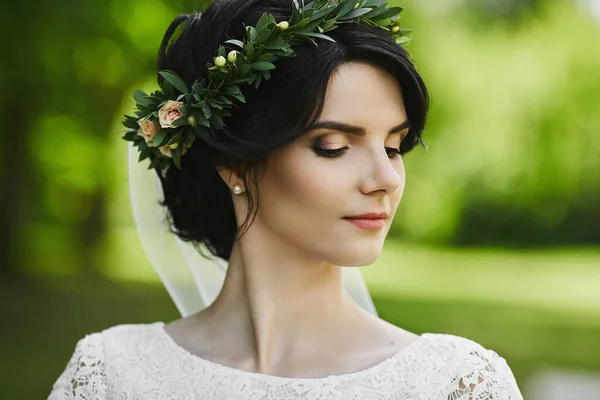 Retrato de close-up de uma bela noiva jovem com coroa floral em seu cabelo posando com os olhos fechados. Mulher jovem com um penteado de casamento e maquiagem brilhante. Conceito de beleza — Fotografia de Stock