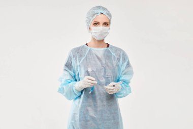 Tıbbi üniformalı kadın doktor ya da cerrah endotrakeal tüp tutan ve beyaz bir arka planda poz veren tıbbi koruyucu maske. Sağlık ve Acil Servis