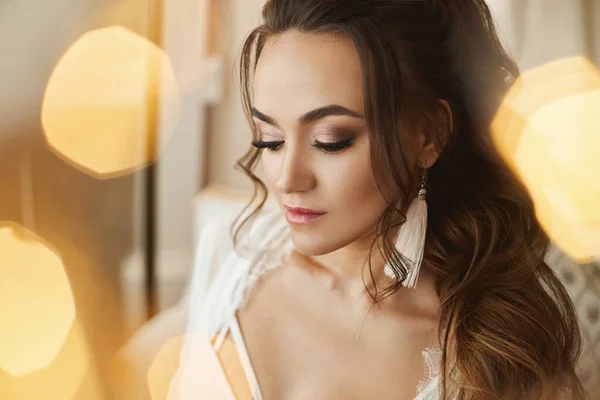 Young woman with perfect face skin, makeup and bridal hairstyle posing with closed eyes on unfocused background. Wedding preparation