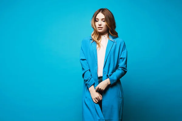 Модель дівчина в синьому пальто і блузка ізольовані на синьому фоні з копіювальним простором. Жіноча мода. Концепція краси. Європейська гіпстерка.. — стокове фото
