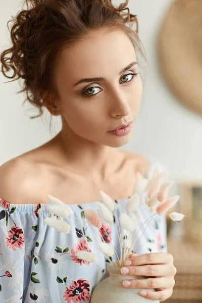 Portrait of young woman with curly hair and green eyes in the interior. Model girl posing with vase. Summertime — Stock Photo, Image