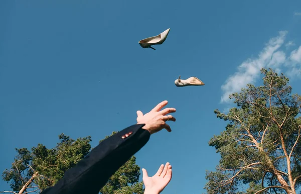 Hombre tirando sus zapatos hasta capturas sus manos cielo fondo — Foto de Stock
