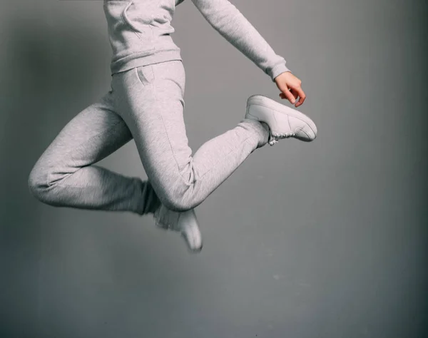 Ragazza tuta sportiva grigio scarpe da ginnastica bianco salto — Foto Stock