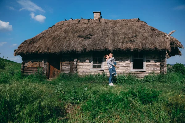 Mãe com seu filho velha casa de madeira telhado de palha — Fotografia de Stock