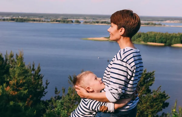 Máma a syn jsou objímání na pozadí velké řeky — Stock fotografie