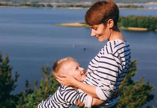 Mamma och son kramar bakgrund av en stor flod — Stockfoto
