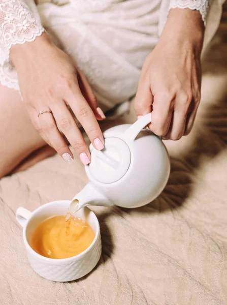 Chica en blanco espuma vierte té sentado — Foto de Stock